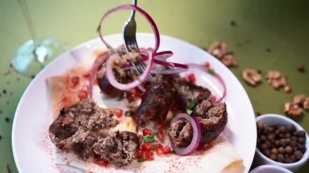 Eating with fork georgian fried pork sausages kupaty with onion and cilantro — Stock Video
