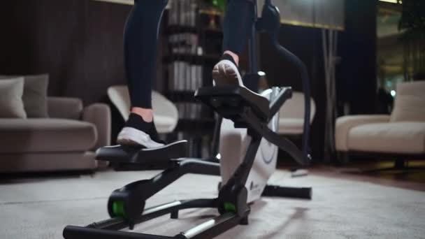 Gros plan jambes féminines en cours d'exécution sur une machine elliptique orbitrek dans la salle de fitness — Video