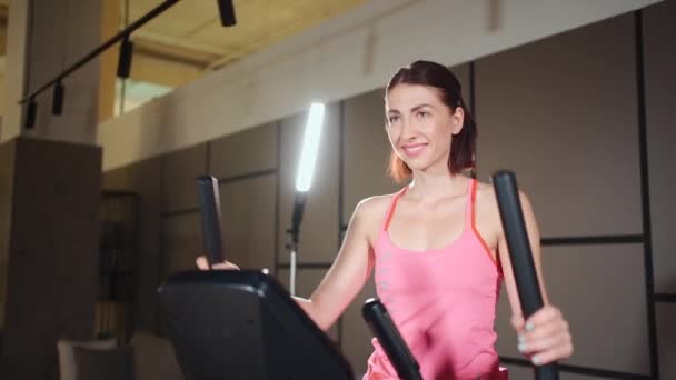 Kobieta biegająca na orbitreku eliptycznym w siłowni lub mieszkaniu fitness — Wideo stockowe
