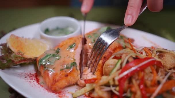 Detailní záběr ručně krájeného pečeného lososového steaku na bílém talíři s wok zeleninou — Stock video