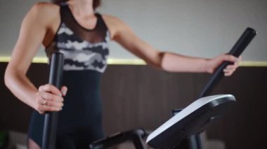 Kadın spor salonunda ya da apartmanda eliptik yörünge makinesinde koşuyor.