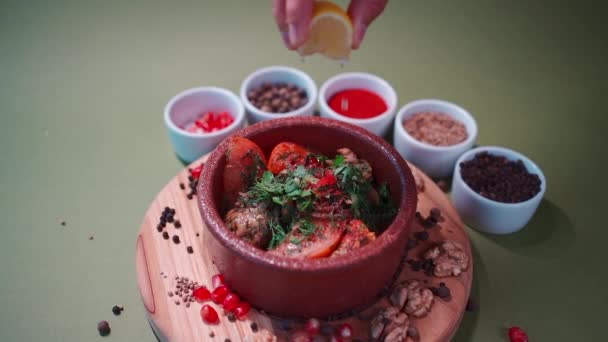 Hand gießt Zitronensaft auf gebratenes Kalbshirn mit Tomate, Koriander und Gewürz — Stockvideo