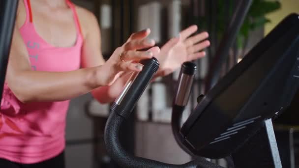 Atlet perempuan berolahraga pada mesin elips dan mengukur sensor detak jantung — Stok Video