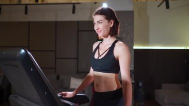Genç fitness kadınının kardiyo çalışması ve evdeki koşu bandında yürümesi var.