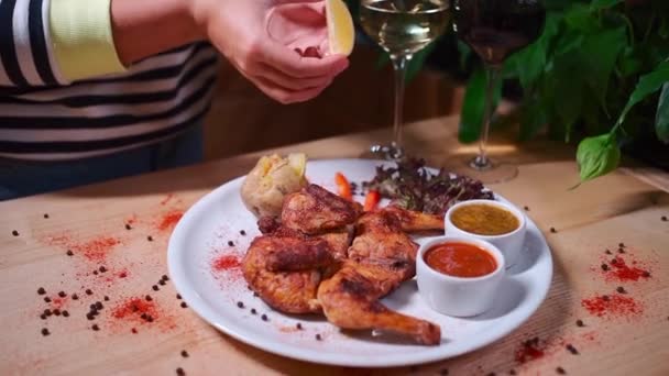 Hand gießt Zitronensaft auf gebratenem Huhn Tabaka auf weißem Teller im Restaurant — Stockvideo