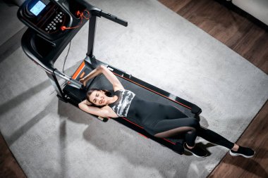 Koşu bandında antrenmandan sonra dinlenen neşeli, yorgun bayan sporcu.