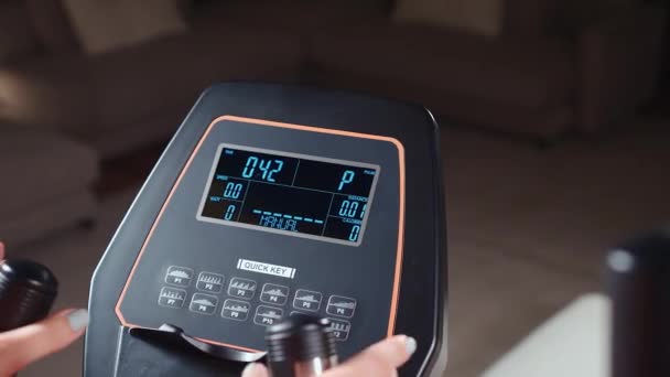 Спортсменка тренується на еліптичній машині та вимірює датчик серцевого ритму — стокове відео
