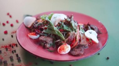 yeşil marullu salata, et, bıldırcın yumurtası ve hardal sosu tabakta.