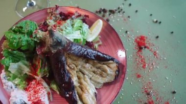 Kırmızı biberli ızgara patlıcan ve karışık marul ve romaine tabakta.