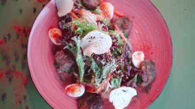 yeşil marullu salata, et, bıldırcın yumurtası ve hardal sosu tabakta.