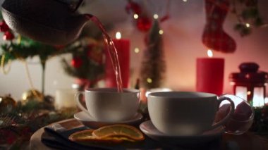 person pour traditional raspberry tea in couple of mugs at new year eve