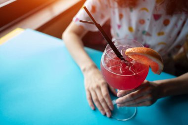 Genç bir kadın barda greyfurt kokteyli içiyor.