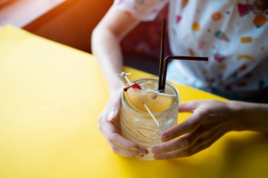 Kız, tekila, şurup ve narenciye ile şeffaf bir kokteyl içiyor.