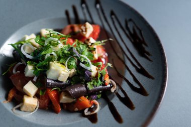 Taze sebze salatası, beyaz peynir ve siyah tabakta balzamik sos, sağlıklı yemek.