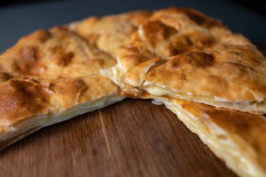 Suluguni peynirli turta ve restoranın koyu arka planında pişmiş kabuk.