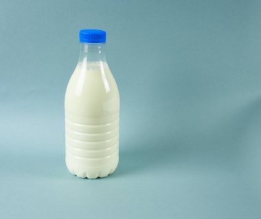  Süt şişesi mavi arka planda, yakın plan.
