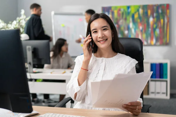 Ofis çalışanı elinde evraklar, raporlar, müşteriler, çağrı merkezleri, telefon üzerinden iş teklifleri, beyaz tişörtlü bir şekilde gülümseyen bir kız ile masada oturuyor.