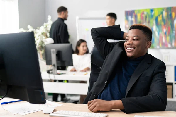 İşten izin almış rahat bir şirket çalışanı, sandalyesinde rahatça oturuyor elini başının arkasında tutuyor, gülümsüyor, gevşiyor, işini bitirmiş, sorumluluklarını yerine getiriyor.