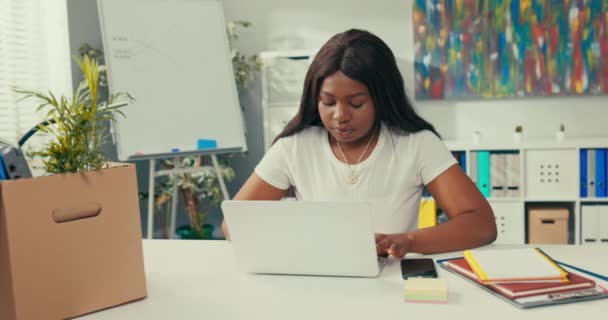Szervezett lány ül a hivatalban a cég körül dokumentumok, ellátás, doboz dolgokat, egy nő összpontosított dolgozik egy laptop csapolja ujjait billentyűzeten, gondoskodik menetrend alkalmazottak. — Stock videók