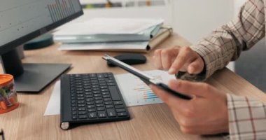 Bir kadının eli tablet tutarken yakın plan görüntüsü, parmaklarını ekrana tıklar, kaydırır, kontrol eder, e-posta, haber, sosyal medya güncellemeleri, bilgisayar ofisi, arka planda klavye.