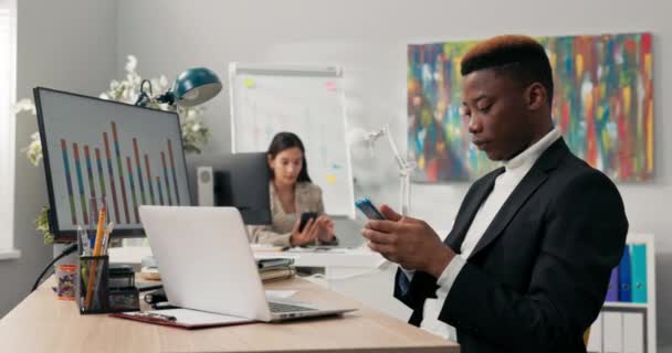 Kontorsarbetare sitter vid sina skrivbord framför datorskärmar, sköter inte sina uppgifter, använder telefoner, surfar i sociala medier, pratar med vänner, tar en paus från jobbet. — Stockvideo