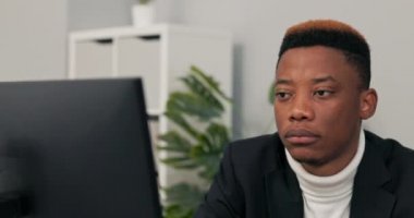 Ofiste, hukuk firmasında çalışan koyu tenli bir adamın yüzüne yakın plan. Çocuk bilgisayarın önünde oturuyor. Elektronik belgelerin doğruluğunu kontrol ediyor..