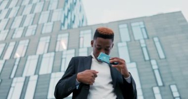 Koyu tenli takım elbiseli bir adam şirketin cam binasının önünde duruyor. Telefon görüşmesi sona eriyor. Arayan kişi cep telefonunu ceketinin cebine koyuyor.