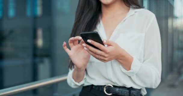 Close-up shot of neat hands of elegant woman holding phone, smartphone, woman taps screen, sends message, dressed in shirt walks past glass building of company, business affairs — Stock Video