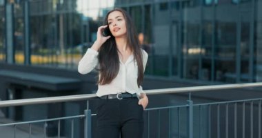 Şirket sekreteri telefon numarasını çeviriyor, arkadaş arıyor, patron molada, kadın şirketin cam binasının önünde duruyor, iyi haberler öğreniyor, mutlu, neşe, neşe, neşe