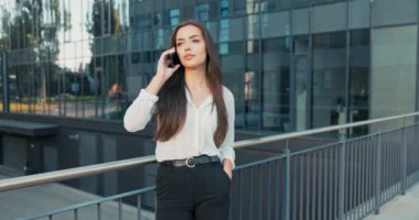 Stresli, şık elbiseli bir kadın cam şirketinin binasının önüne doğru yürür. Telefon eder, patronunu arar. İyi haberler öğrenir.