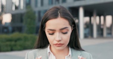 Koyu renk gözlü güzel bir esmer şehrin arka planında duruyor, cam bir bina, zarif bir kıyafet giymiş bir kadın, yüzüne koruyucu bir maske takıyor, iş, virüs salgını sırasında hayatı boyunca.