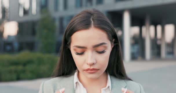 Une jolie brune aux yeux sombres se tient en arrière-plan de la ville, un immeuble en verre, une femme vêtue d'une tenue élégante, met un masque de protection sur son visage, son travail, sa vie lors d'une pandémie de virus — Video