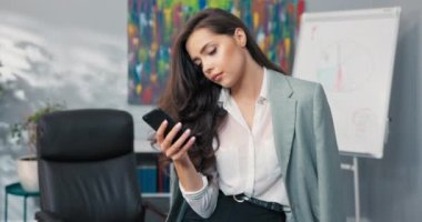 Patrona, sekretere, yöneticiye odaklanmış bir asistan ofiste masada oturuyor, telefonla sosyal medyaya bakıyor, mesajlara cevap yazıyor, iş yerinde akıllı telefonuyla oynuyor.