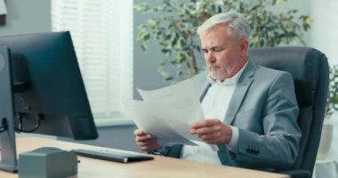 Tecrübeli bir işadamı, gri saçlı bir şirket başkanı, başkanın rahat koltuğunda oturuyor, kendisine sunulan belgelere bakıyor, dikkatle okuyor, bir meslektaşına soruyor.