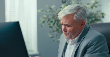 Şirketin gri saçlı başkanı, başkanın rahat koltuğunda oturuyor, ona sunulan belgeleri gözden geçiriyor, dikkatle okuyor, video konferansı sırasında meslektaşından çizelgeleri açıklamasını istiyor.