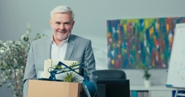 Tecrübeli bir yönetmen, menajer, şirketin başı, gri saçlı yaşlı bir adam elinde bir karton kutu, içine bakıyor, gülümsüyor, dinleniyor, tatil yapıyor, emekli oluyor.