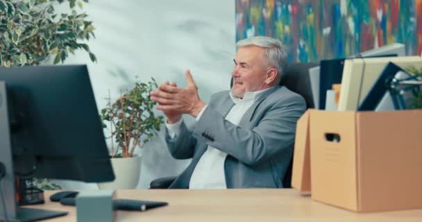 Усміхнений керівник компанії сидить у зручному поворотному кріслі, що нагадує йому про роки служби елегантний чоловік проводить останній день на роботі, перш ніж вихідні оплески радіють — стокове відео