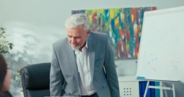 Yetişkin, tecrübeli, takım elbiseli, beyaz saçlı bir patronla röportaj yapan genç bir kadın adaylara şirket ve eğitim hakkında sorular soruyor.