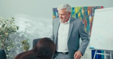 İş görüşmesi, gri saçlı yaşlı patron selamlaşmak için genç bir kadınla tokalaşıyor, oturmak istiyor, erkek sorular soruyor, pozisyona başvuran kız eğitimini, tecrübesini anlatıyor.