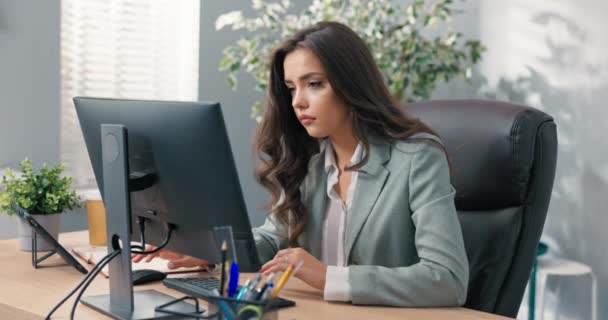 Занятая деловая женщина сидит за столом перед компьютером в офисе, она имеет технические проблемы с монитором, неправильная настройка экрана, нет сигнала, ошибка, женщина смеется не может делать свою работу — стоковое видео
