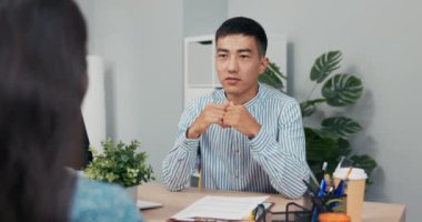 Tekerlekli sandalyedeki engelli kadınla iş görüşmesi, Asya-Koreli güzellikteki gülümseyen patron kıza sorular sorar şirket ofisinde masanın iki tarafında oturur, dikkatle cevap verir.