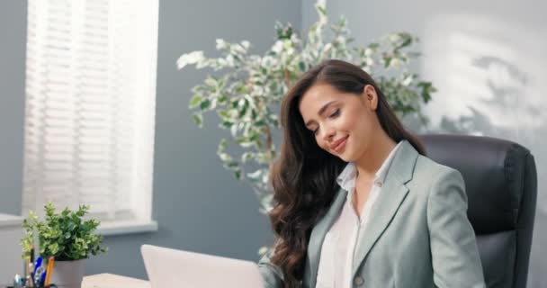 Trabalhador de escritório corporativo atraente senta-se na mesa na frente da tela do laptop olha para a câmera encantadoramente sorrindo flertando bela secretária gerente de cabeça corporativa com olhos de cabelo marrom bonita — Vídeo de Stock