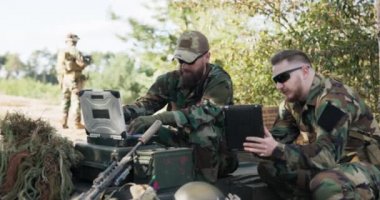 Güçlü orduya mensup askerler sürpriz düşmanla savaşmak için strateji hazırlıyorlar. Verileri sisteme girin. Konuşun. Tabletleri üniformalı, üniformalı, kamuflajlı, miğferli, sırt çantalı, eğitim sahasında tutun.