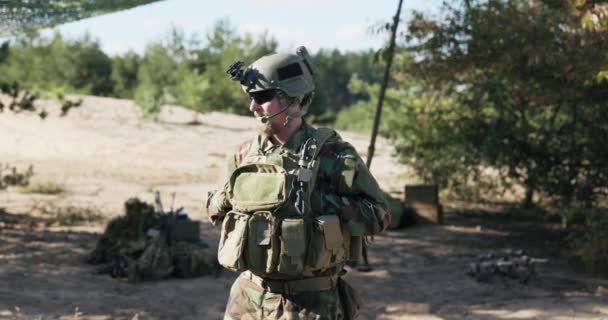 Un homme en costume marocain avec un casque sur la tête, un talkie-walkie parle à un collègue, il a une ceinture d'arme, un sac à dos de munitions porté devant la poitrine, un soldat armé — Video