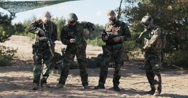 Moro üniforması giymiş dört asker, bölgeyi savunmaya hazır bir ordu, silahları kontrol ediyorlar, kilidi açıyorlar, kısa tabancalar, uzun tüfekler, kemerin cebinde saklanıyorlar. — Stok video