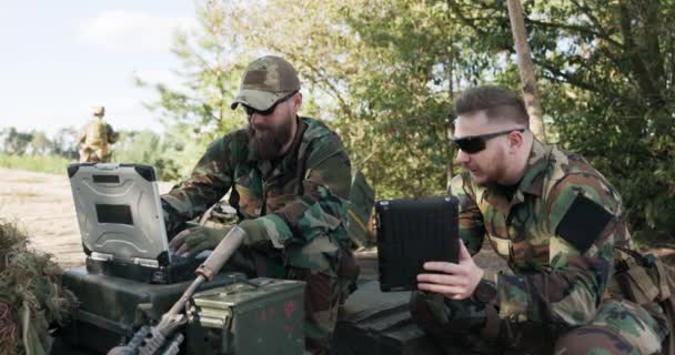 Soldater som tillhör mäktiga armén förbereder strategi för att bekämpa överraskande fiende in data i systemet talk hold tablett klädd i uniformer moro, kamouflage, hjälmar, ryggsäckar, utbildning marken — Stockvideo