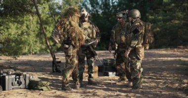 Toprak savunma adamlarından oluşan üs grubunda askerlerin toplanması, taktikler, eylem planı, çim kamuflajlı kumandan elinde bir bilgisayar tutuyor ve strateji ve bölgenin topografisini tartışıyor.