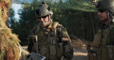 Toprak savunma adamlarından oluşan üs grubunda askerlerin toplanması, taktikler, eylem planı, çim kamuflajlı kumandan elinde bir bilgisayar tutuyor ve strateji ve bölgenin topografisini tartışıyor.