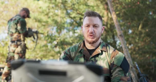 Poważny doświadczony dowódca armii jest na polu rozmowy wideo na komputerze z szefem bazy wojskowej, podając mu szczegóły działań omawiających podjęte środki ostrożności, tajne informacje — Wideo stockowe