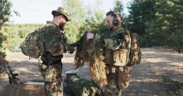 Soldats se préparent à aller en mission sur le terrain, plan pour surprendre l'ennemi, habiller en vêtements équipement appliquer camouflage mousse de gazon artificiel ressemblent à l'environnement forestier, veulent être invisibles aux autres troupes — Video